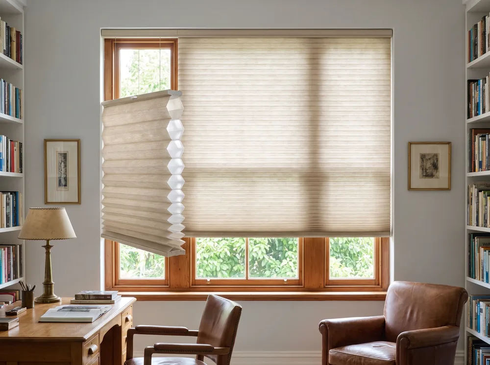 Cellular honeycomb blind partly raised over a study window in a Newlands home